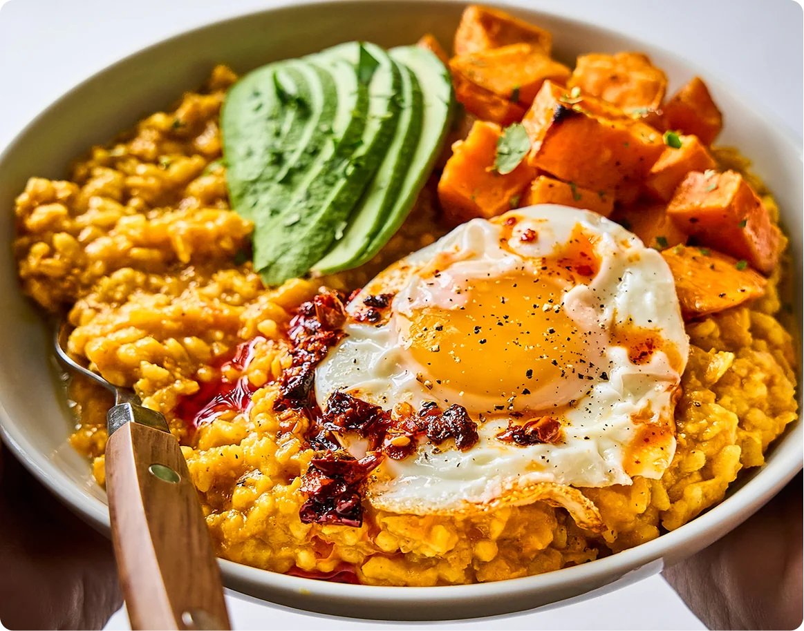 A Yogi Mix savory breakfast bowl topped with avocado, roasted sweet potato and a fried egg